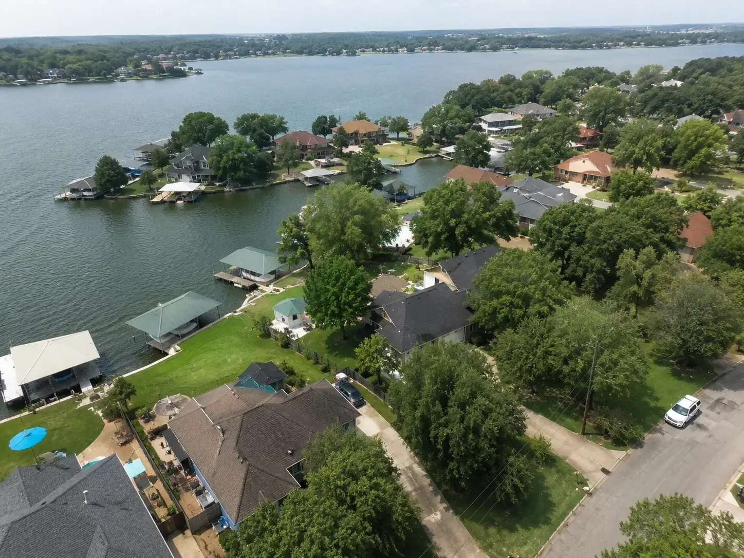 Aerial drone view of waterfront homes and residential neighborhoods near Lake Conroe in Conroe, Texas, showcasing the area's diverse real estate market.