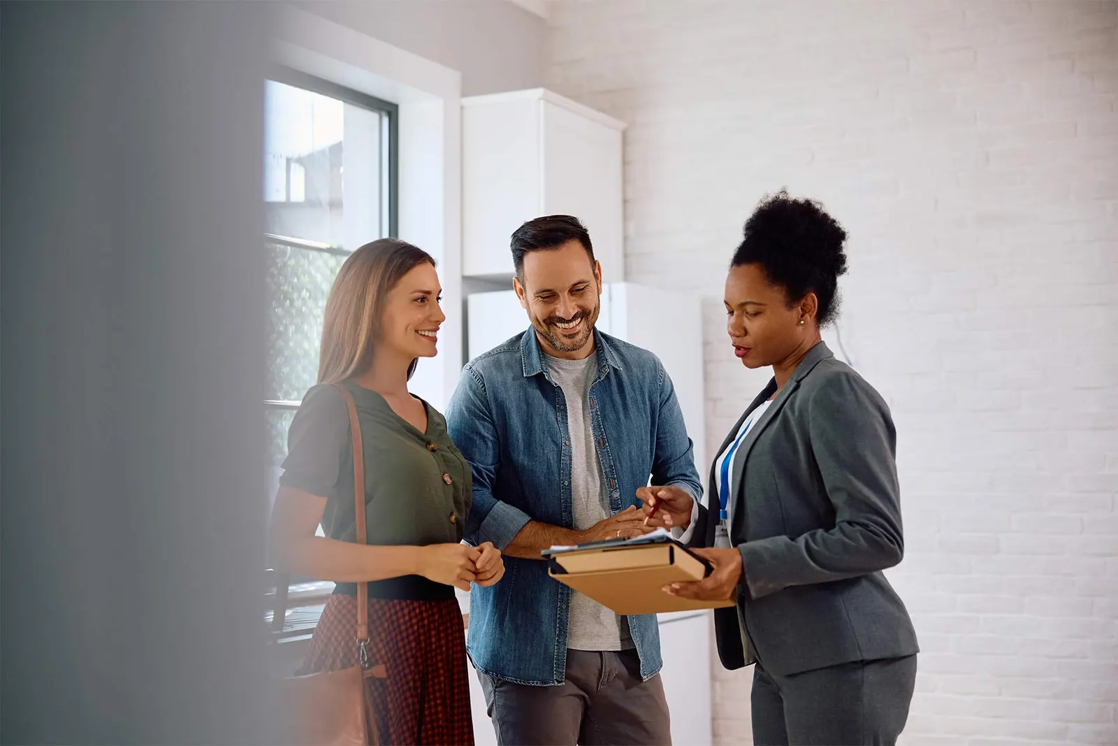 Real estate agent discussing property details with a couple inside a modern home..